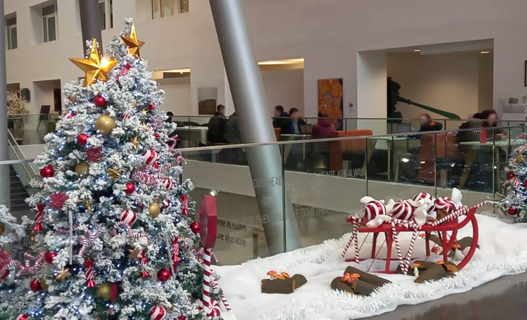 A red, white and gold snowy Christmas scene with flocked trees, sleigh, and giant sweets.